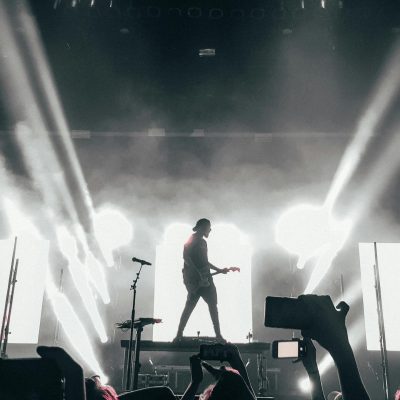 Silhouette of a musician performing live on stage with energetic audience. Captures the essence of nightlife entertainment.