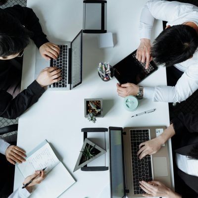 A diverse team working together in a modern office setting, focusing on laptops and collaboration.